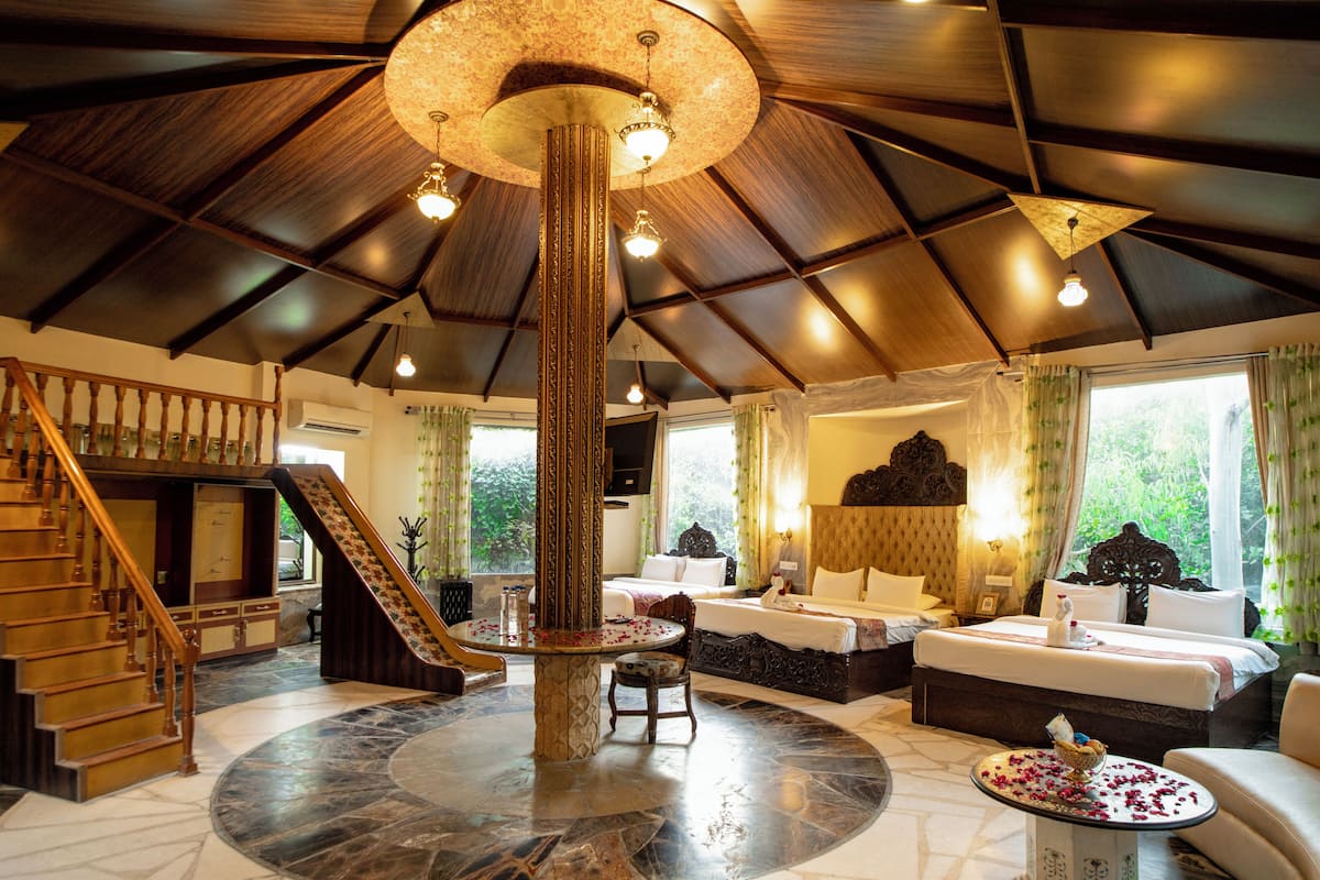 A spacious room with a large circular marble floor, a central column, and a staircase leading to an upper level.