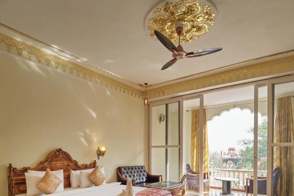 A spacious bedroom with a large bed, a ceiling fan, and a view of the outside through a sliding glass door.