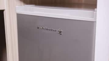 Un réfrigérateur compact et moderne, doté d’une finition métallique et arborant la marque « Kelvinator » sur sa façade.