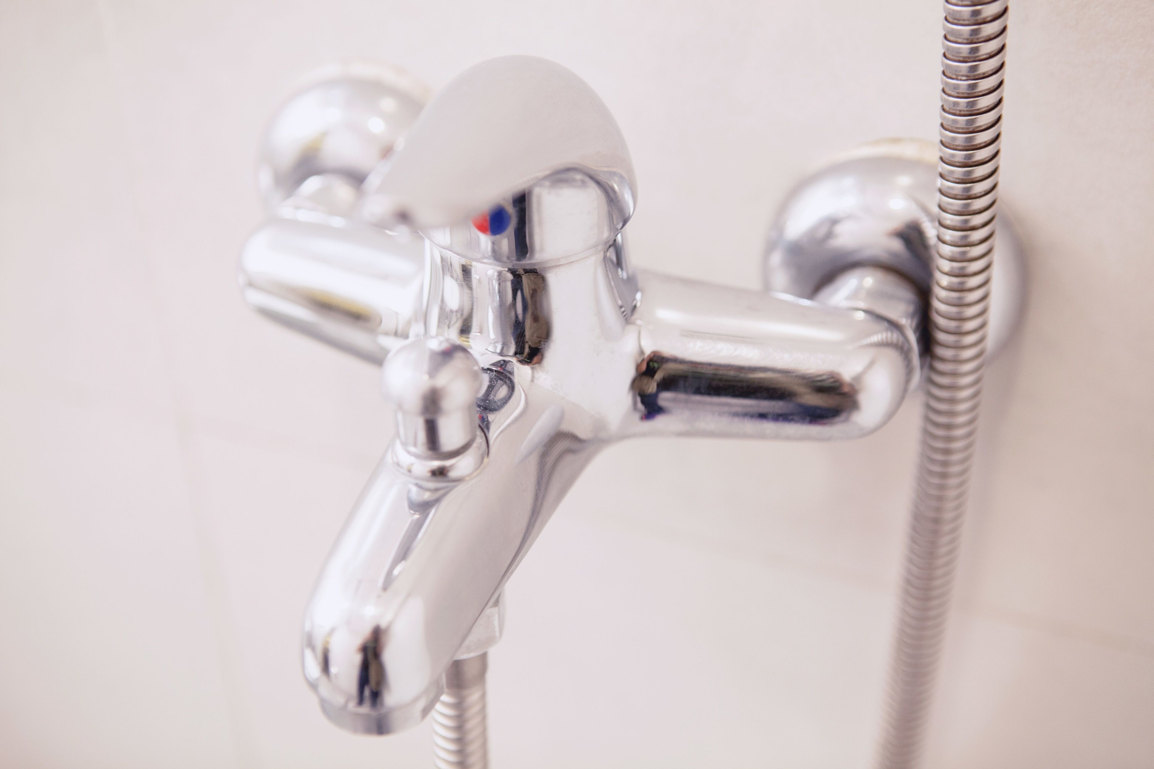 Un robinet chromé muni d’un tuyau flexible, probablement destiné à une douche ou à un évier.