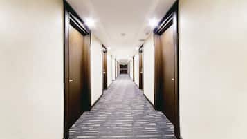 A long, narrow hotel corridor with carpeted floors and wooden doors on both sides.