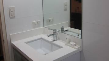 A bathroom with a white sink, mirror, and toilet.
