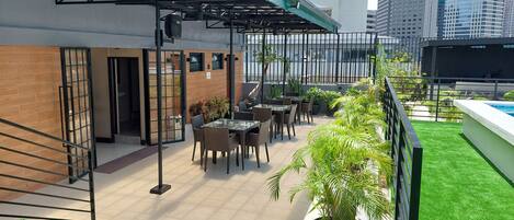 A rooftop patio with outdoor seating, a pool, and city views.
