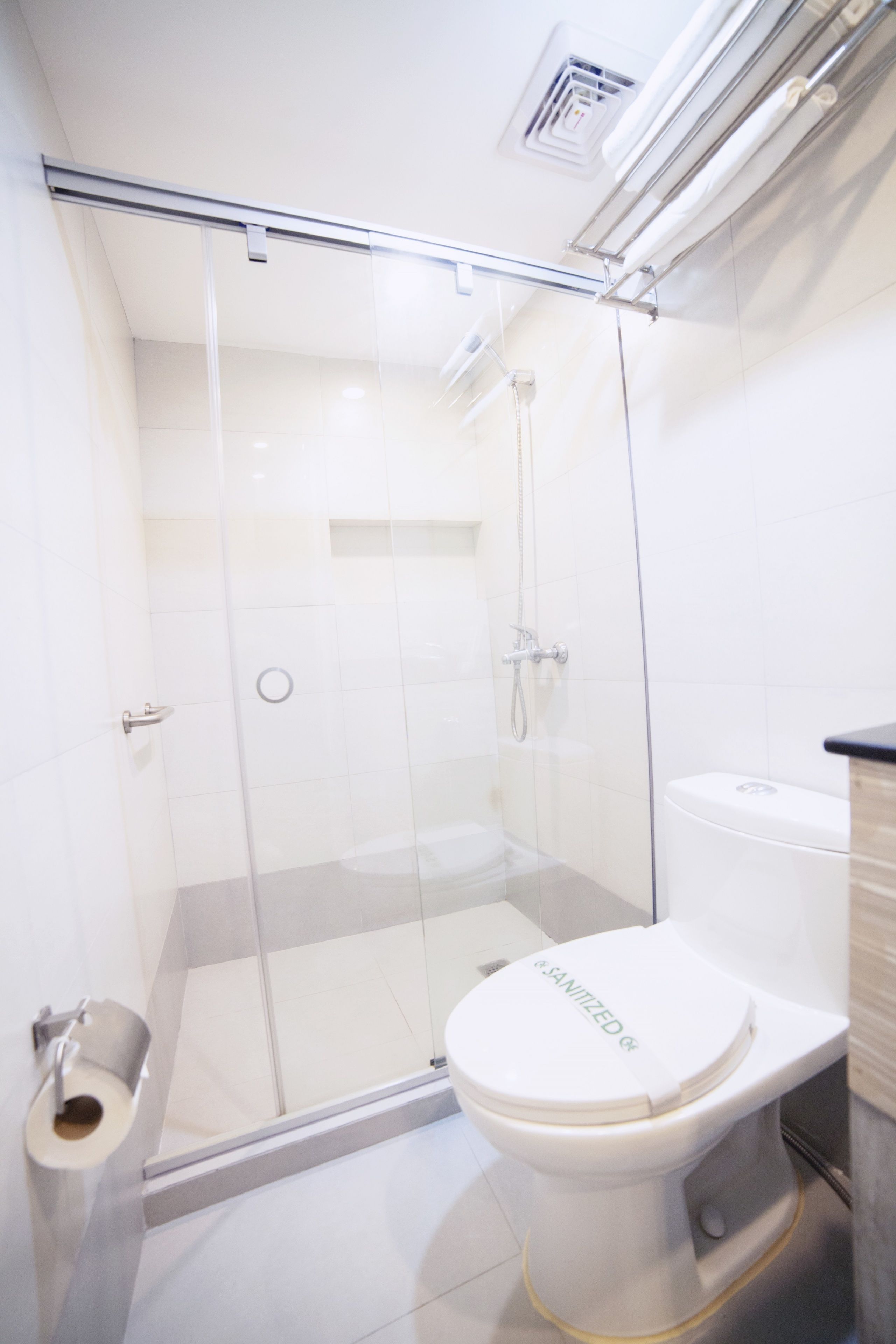 A modern bathroom with a glass-enclosed shower, a toilet, and a sink.