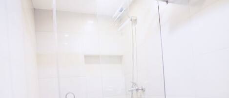 A modern bathroom with a glass-enclosed shower, a toilet, and a sink.