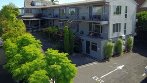 Un hotel de varios pisos con balcones, un acceso cubierto y un área de estacionamiento.