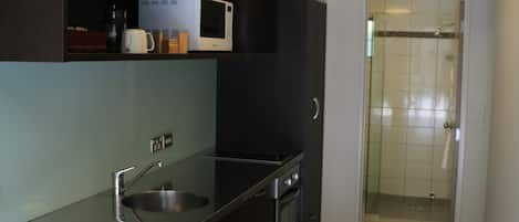 Cocina compacta con microondas, cafetera y lavabo.