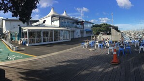 Un puerto deportivo con barcos amarrados, una zona de estar cubierta y un edificio de diseño moderno.