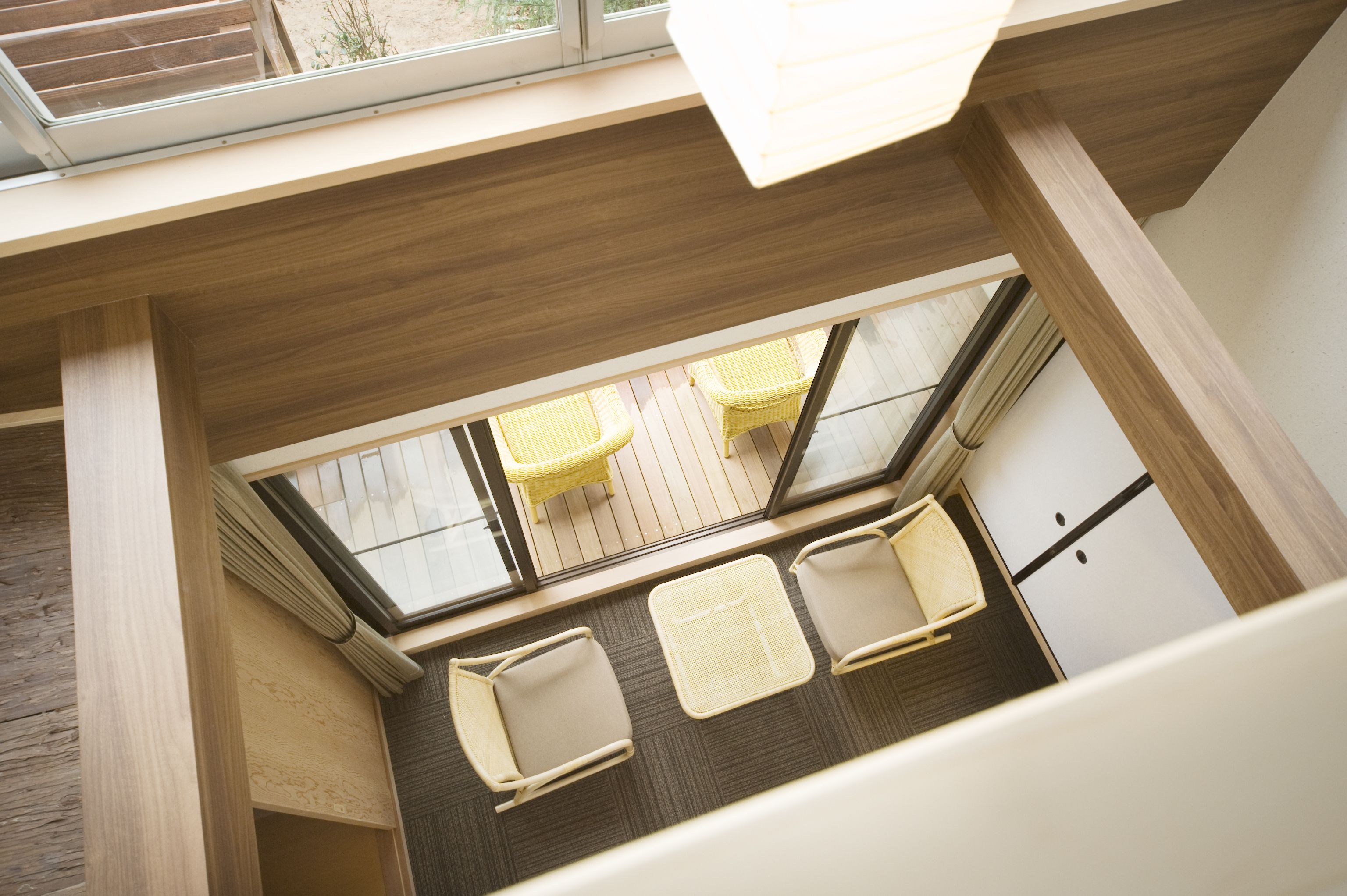 Ein Zimmer mit hohen Decken, einem Oberlicht, Holzboden und Blick auf eine Terrasse mit Stühlen.