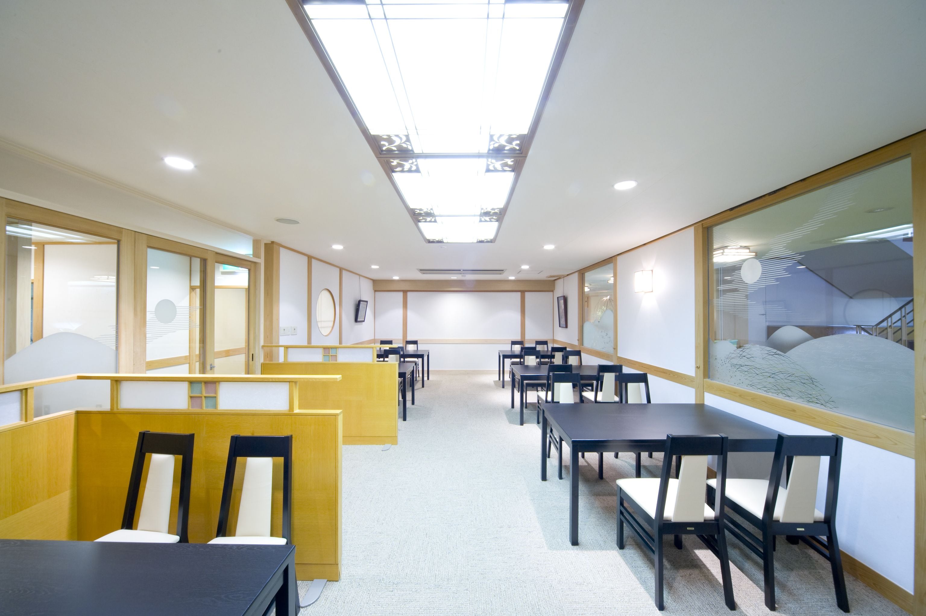 A conference room with multiple tables and chairs, a skylight ceiling, and framed artwork on the walls.