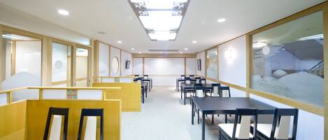 A conference room with multiple tables and chairs, a skylight ceiling, and framed artwork on the walls.