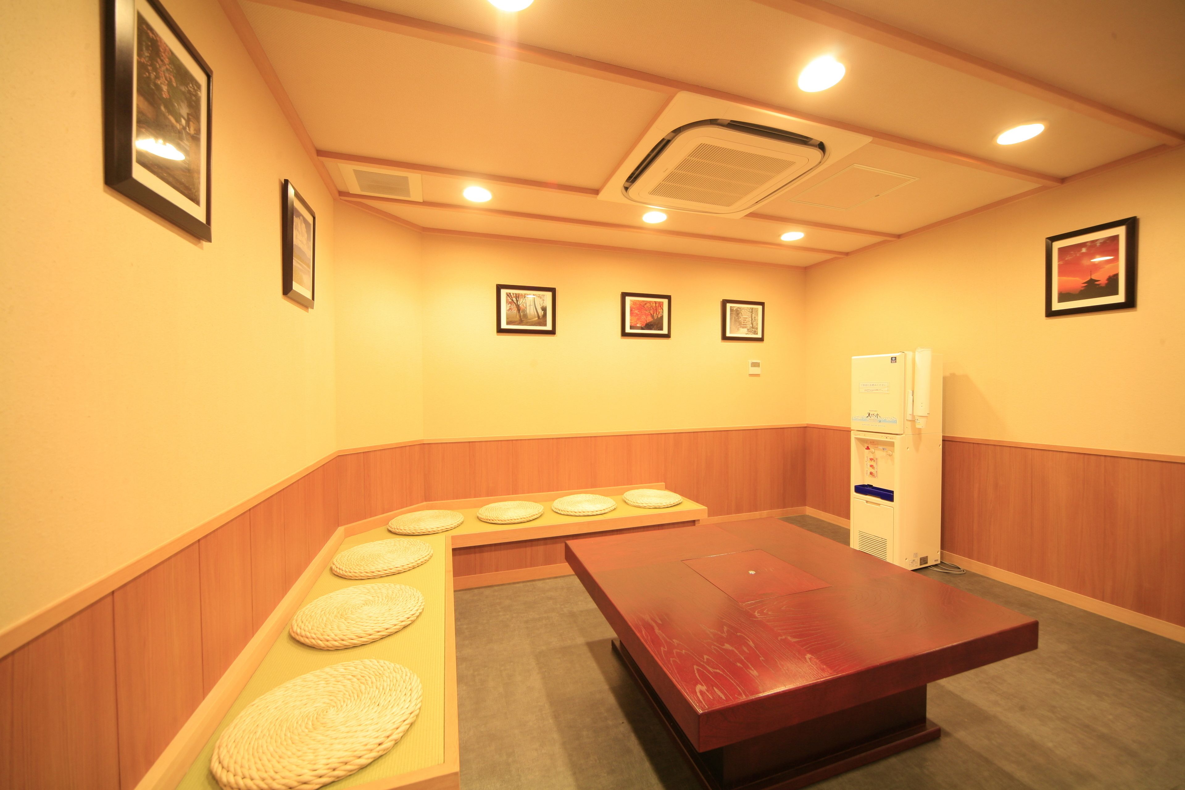 Una sala de conferencias con una mesa de madera, asientos acolchados, cuadros en las paredes y un refrigerador.