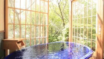 A hot tub in a wooden deck area with large windows.