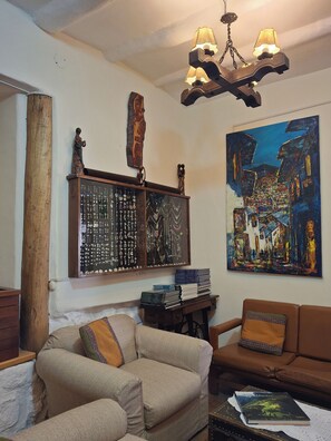 Un salon comprenant un canapé, une table basse, un présentoir à bijoux fixé au mur et un tableau.