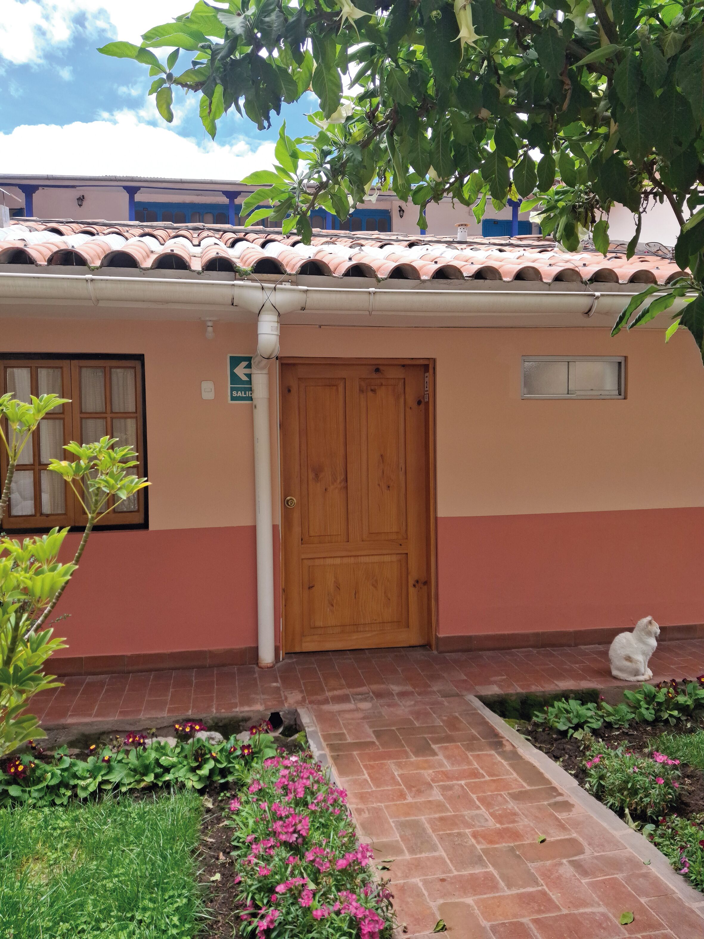 Un edificio con puerta de madera, una ventana pequeña y un letrero que indica un baño.