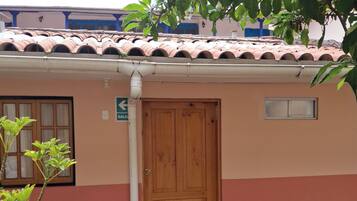 Un edificio con puerta de madera, una ventana pequeña y un letrero que indica un baño.