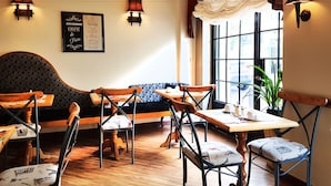 A cozy cafe with wooden furniture, a patterned sofa, and a chandelier.
