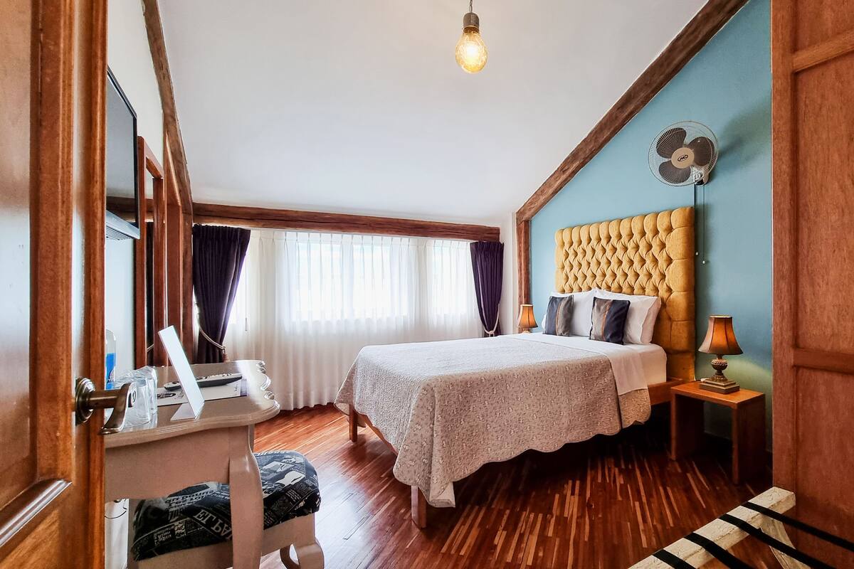 A bedroom with a bed, bedside tables, a desk, and a chair.