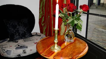 A round wooden table with a white candle and a vase of red roses.