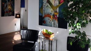 A room with a black leather chair, a small table with a bowl of green apples, and two paintings on the wall. - Casa Fusión (La Paz)