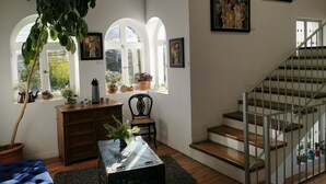 A spacious living room with a staircase, wooden furniture, and multiple potted plants. - Casa Fusión (La Paz)