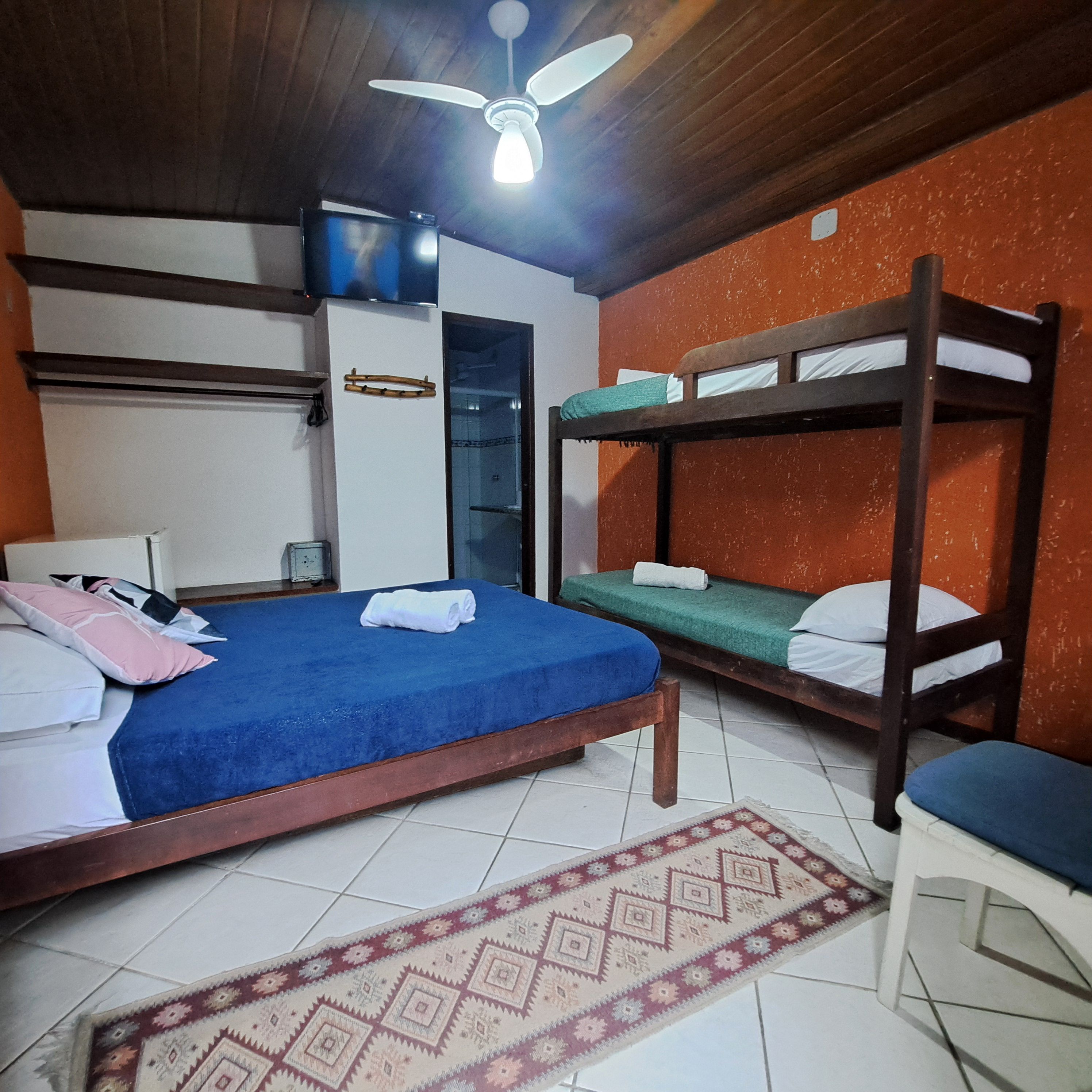 A room with bunk beds, a ceiling fan, a TV, and a patterned rug.
