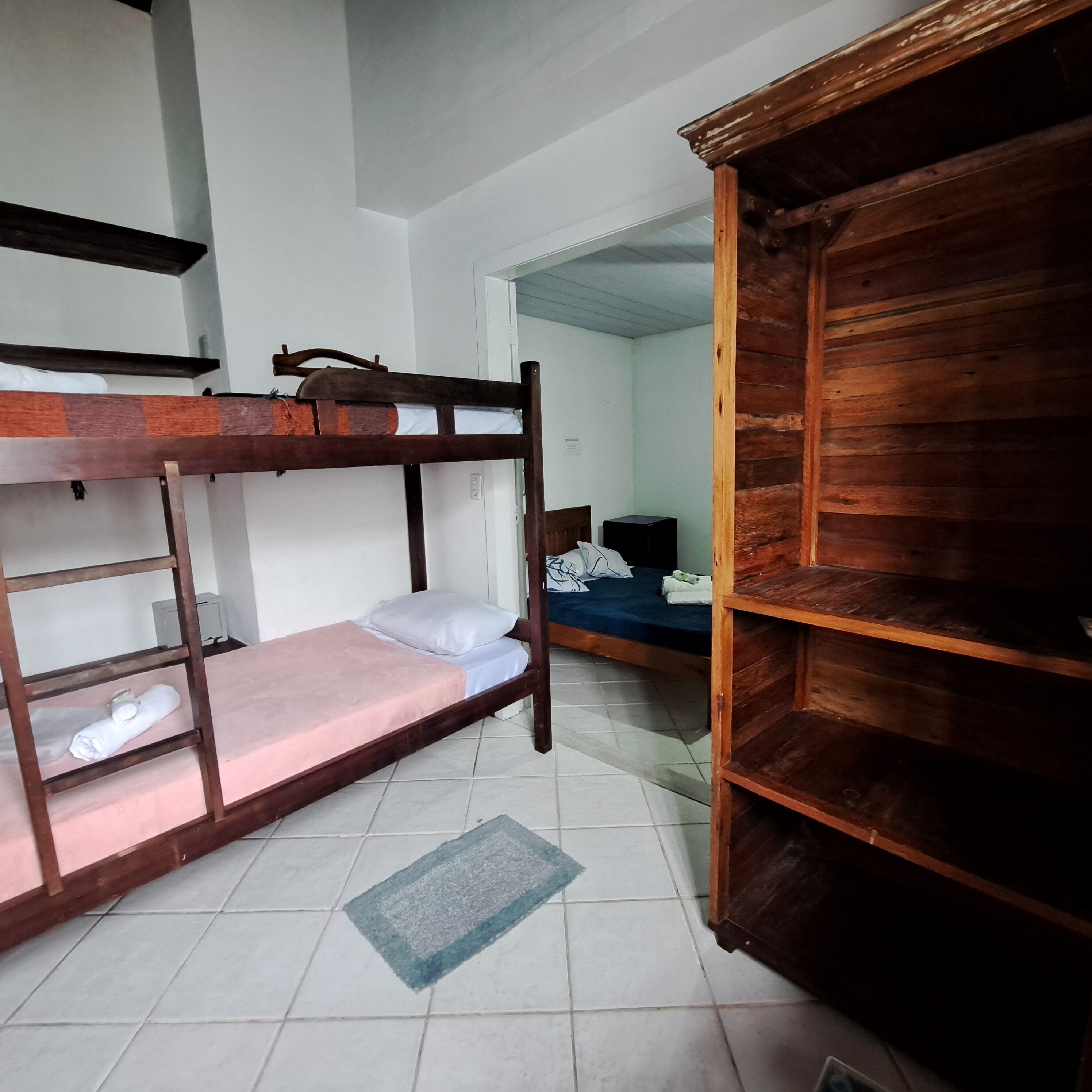 Une chambre avec un lit superposé, une étagère en bois, un bureau et une chaise.