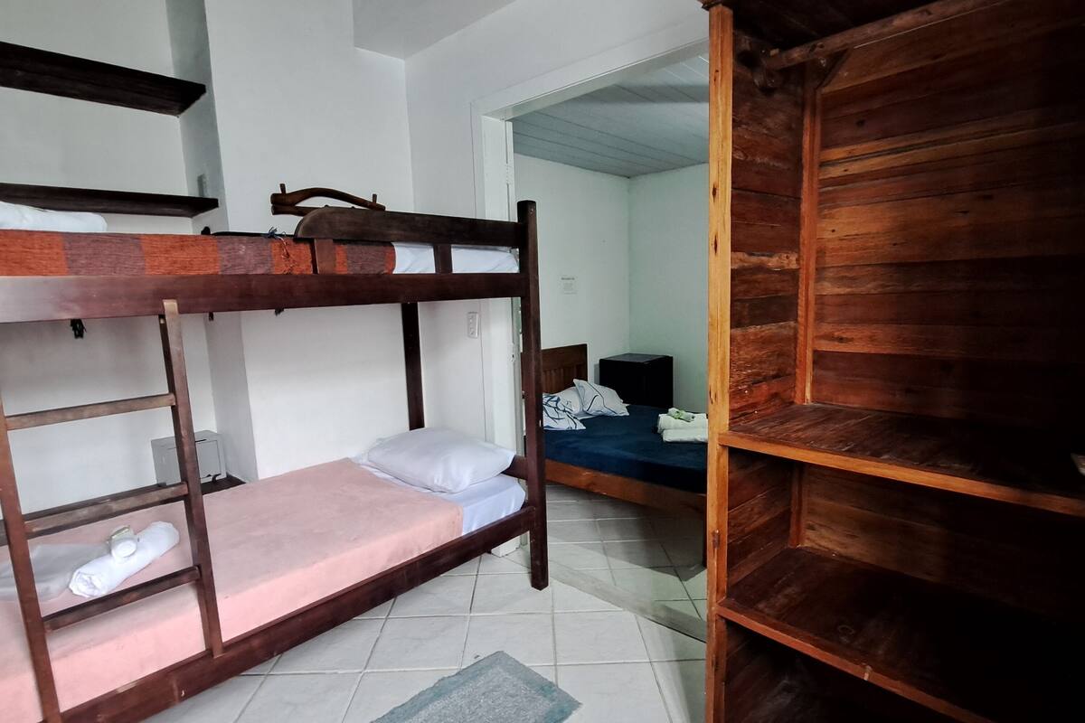 A bunk bed room with a wooden shelf, a desk, and a chair.