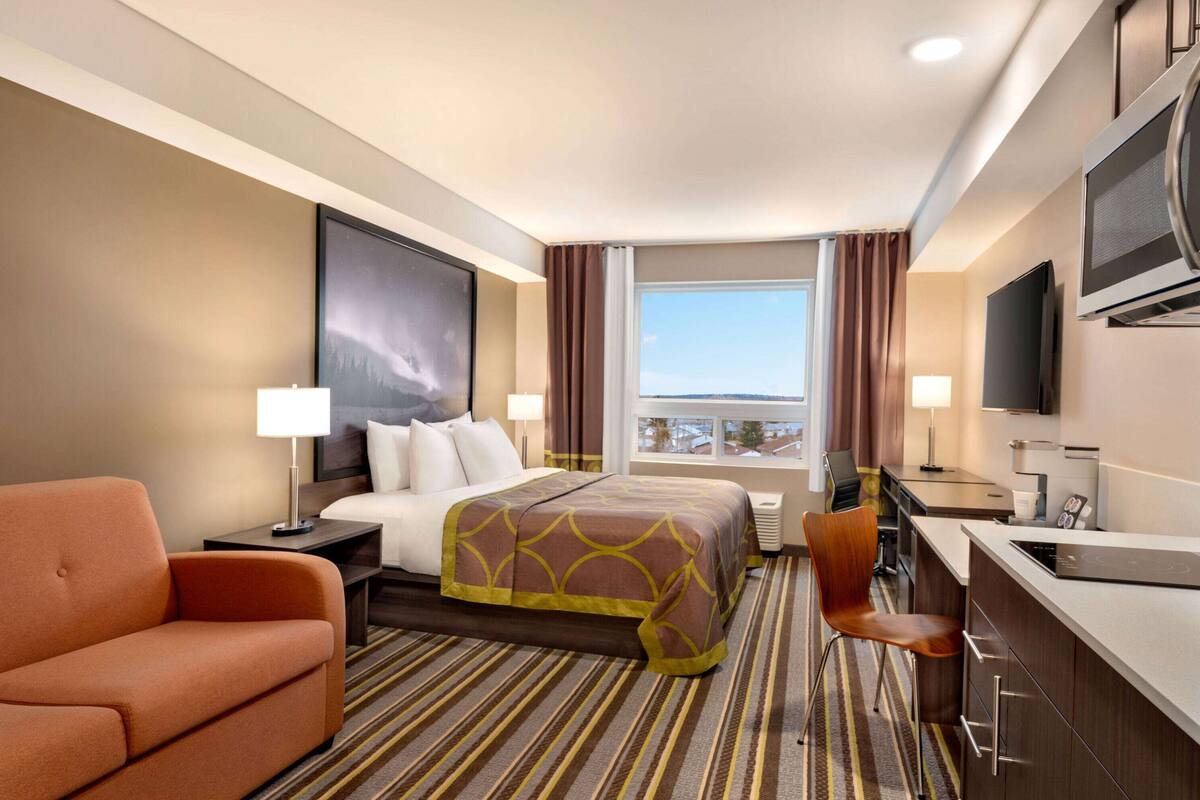 A hotel room with a bed, a desk, a chair, a television, and a window with a view.