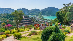 A lush garden with a heart-shaped sign, a view of a coastal area, and mountains in the background. - PP Charlie Beach Resort (Ko Phi Phi)