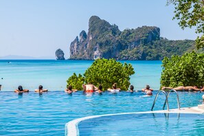 Una piscina con agua azul cristalina, rodeada de exuberante vegetación y un acantilado rocoso al fondo.