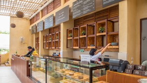 A cafe with a counter, menu boards, and a variety of food displayed in the window. - PP Charlie Beach Resort (Ko Phi Phi)