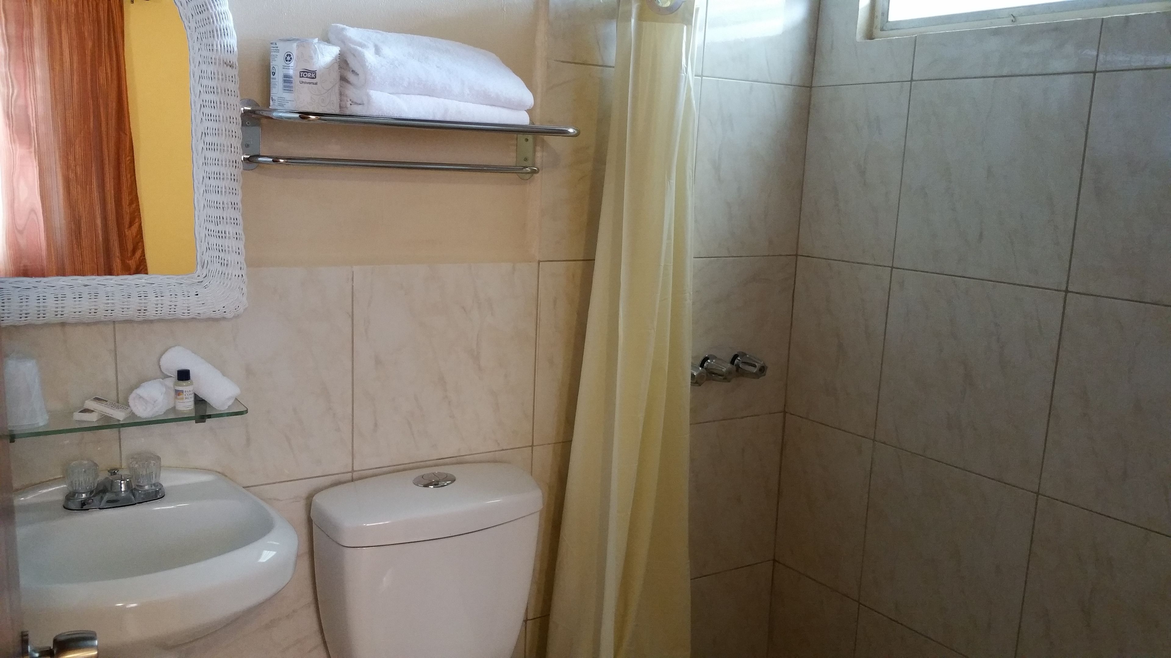 Casa de banho com sanita, lavatório e prateleira com artigos de higiene pessoal.