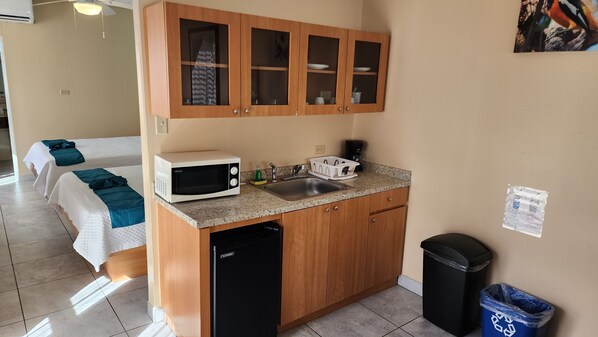 Una cocina compacta con microondas, lavamanos y armarios.