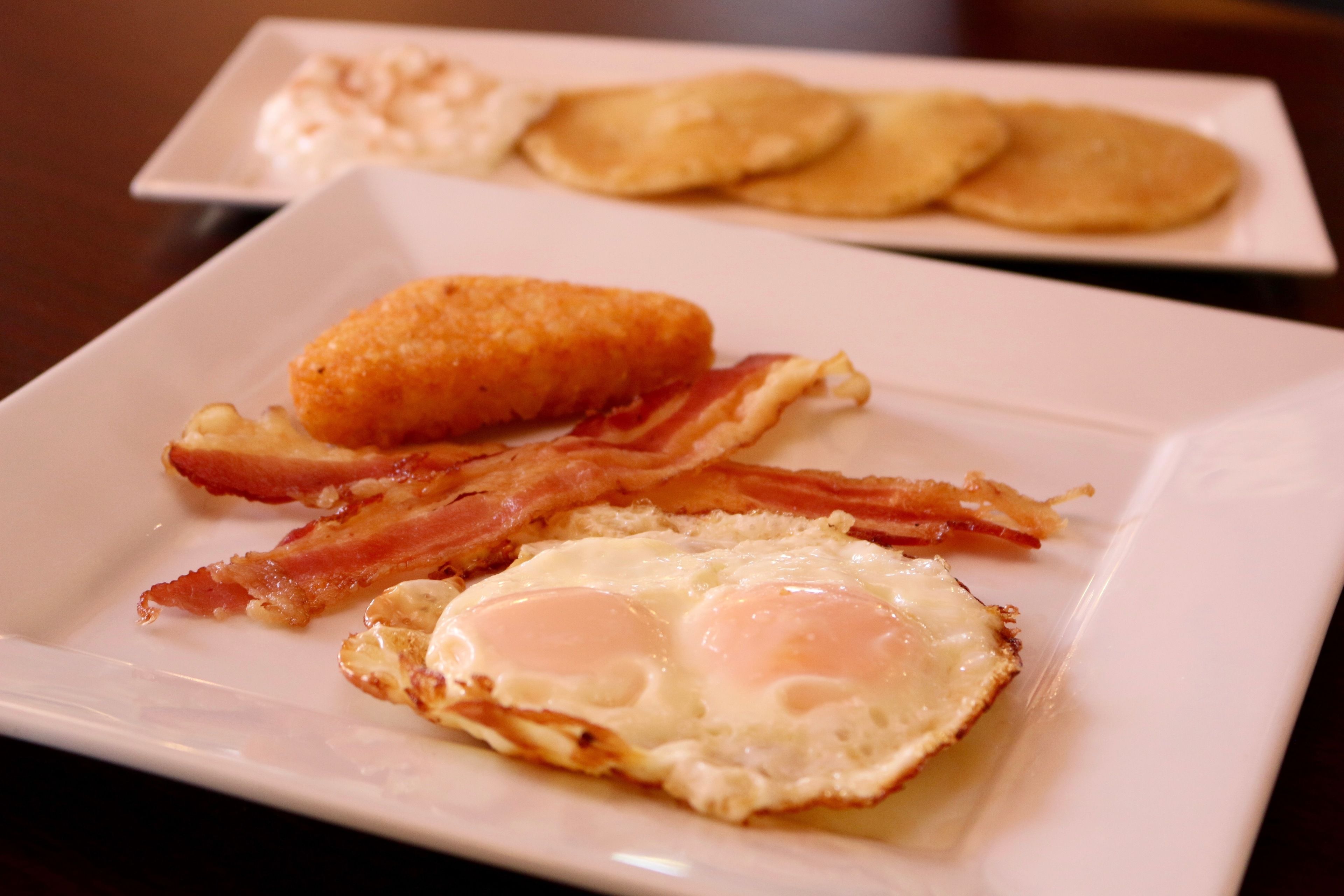 Ein Teller mit Eiern, Speck und Pfannkuchen.