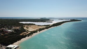 An aerial view of a coastal area with a beach, a small town, and a large body of water.