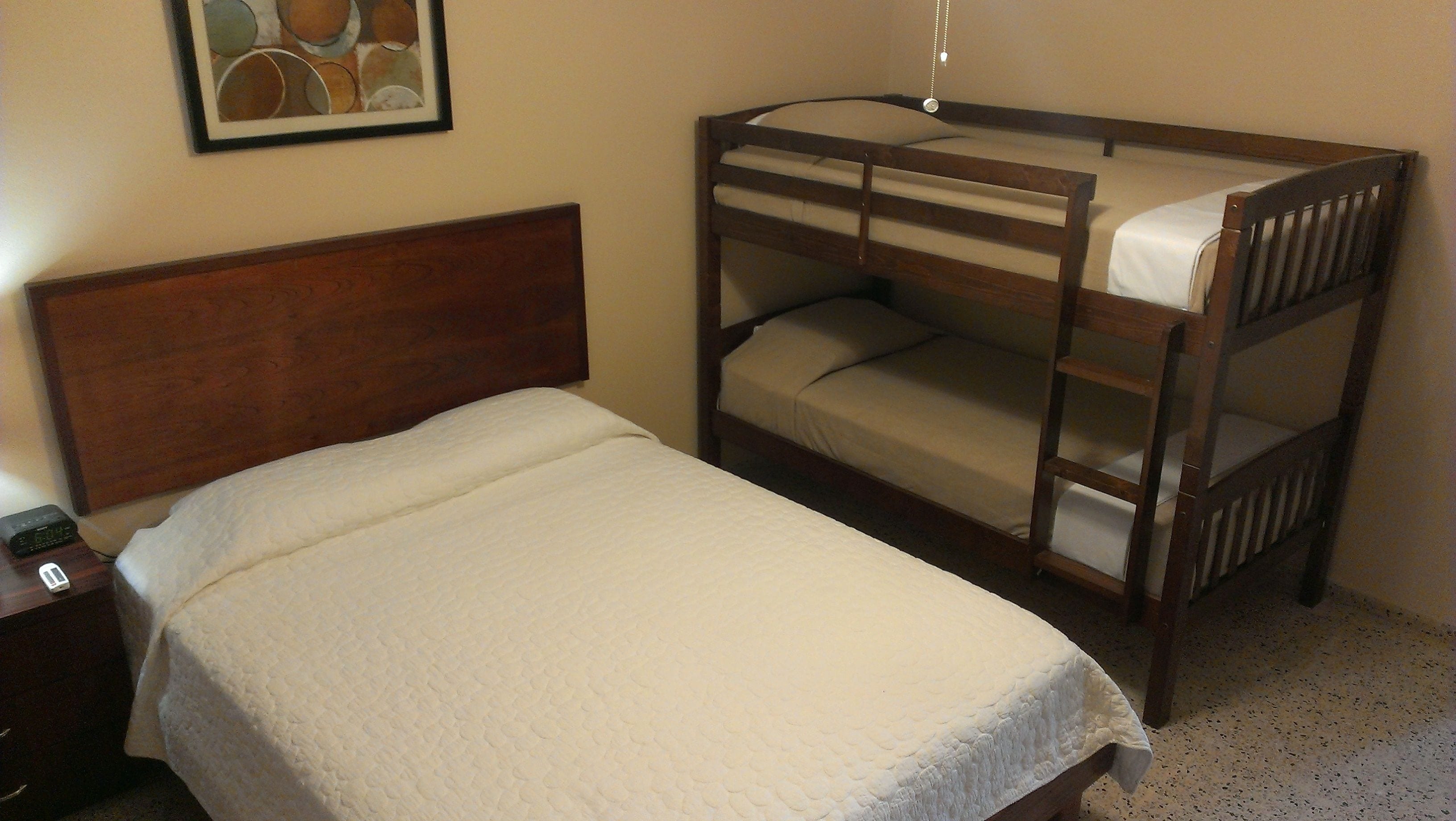 A bunk bed with a wooden headboard and a single bed with a quilted mattress.