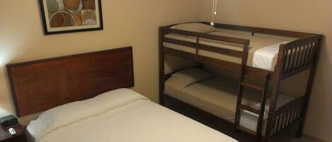 A bunk bed with a wooden headboard and a single bed with a quilted mattress.