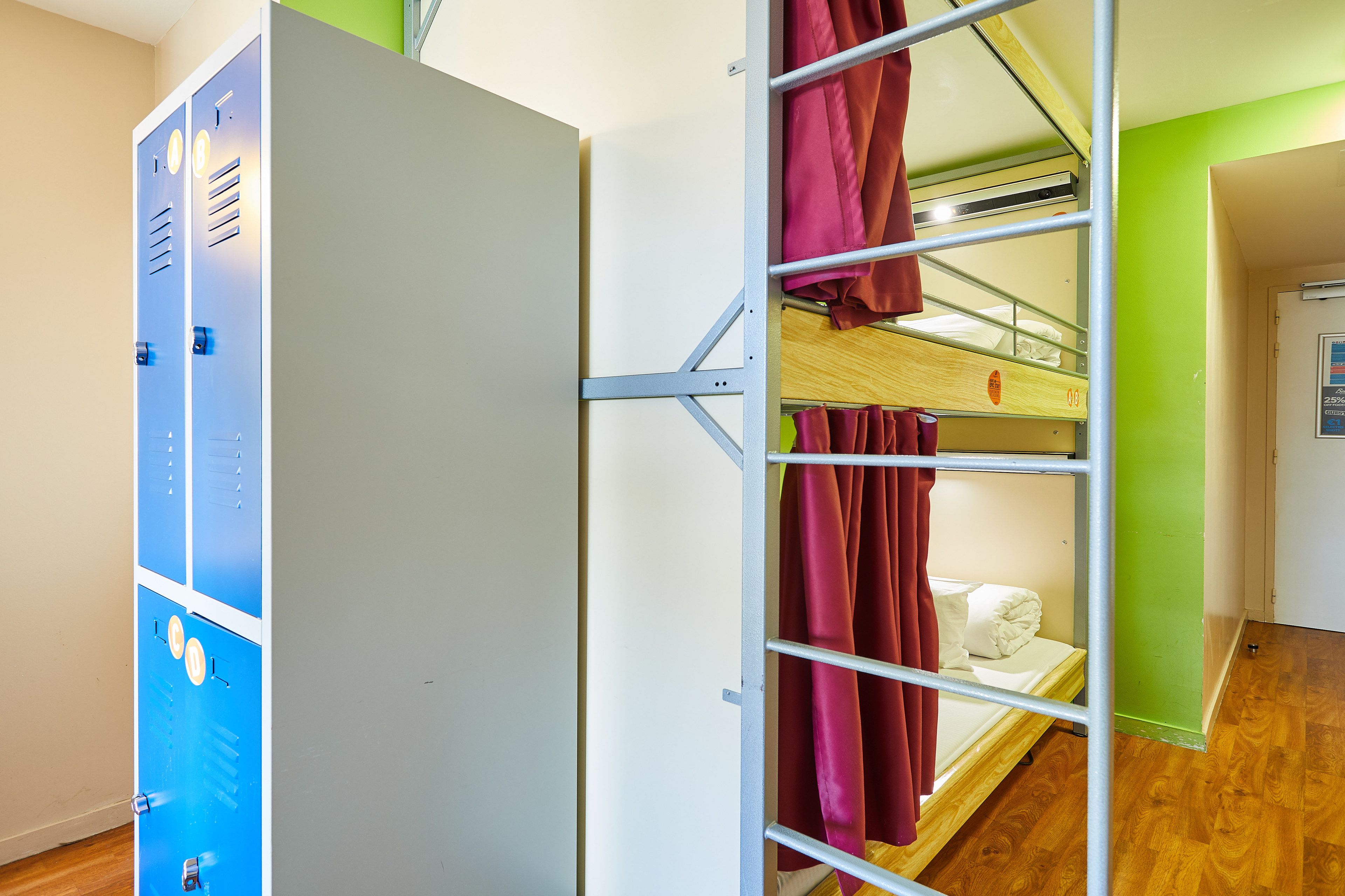 A dormitory room with bunk beds, a wardrobe, and a door.