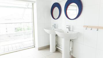 Une salle de bain moderne avec deux lavabos, un grand miroir et une vue sur l’extérieur.