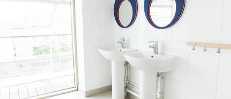 A modern bathroom with two sinks, a large mirror, and a view of the outside.