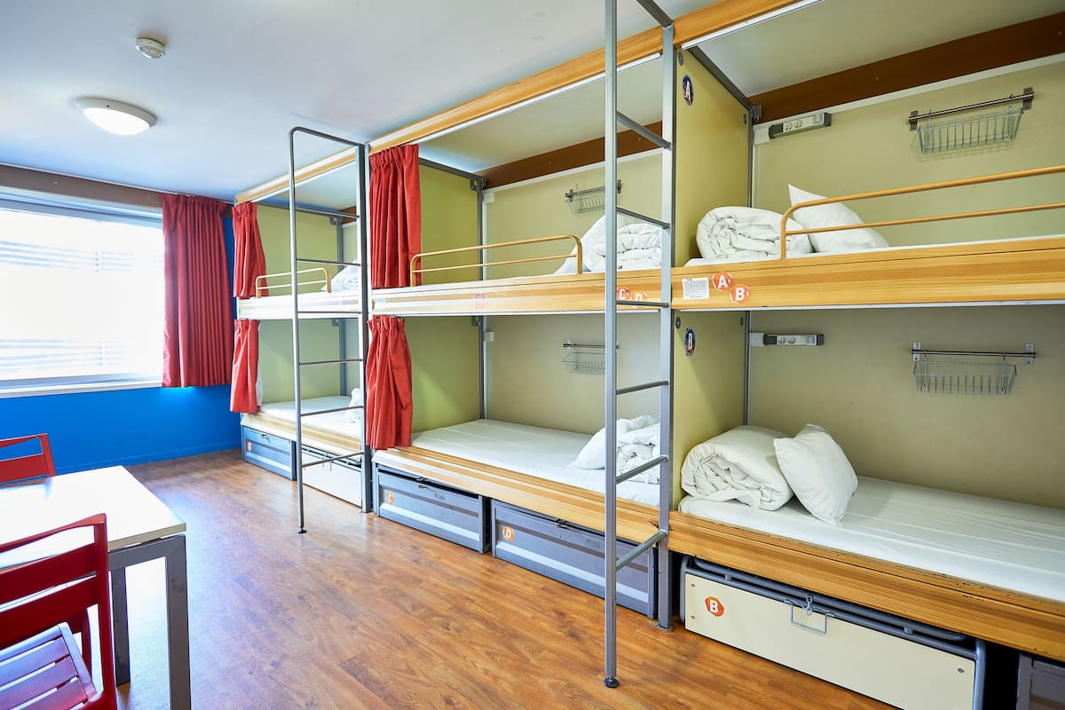 Un dormitorio con literas, una mesa y sillas.