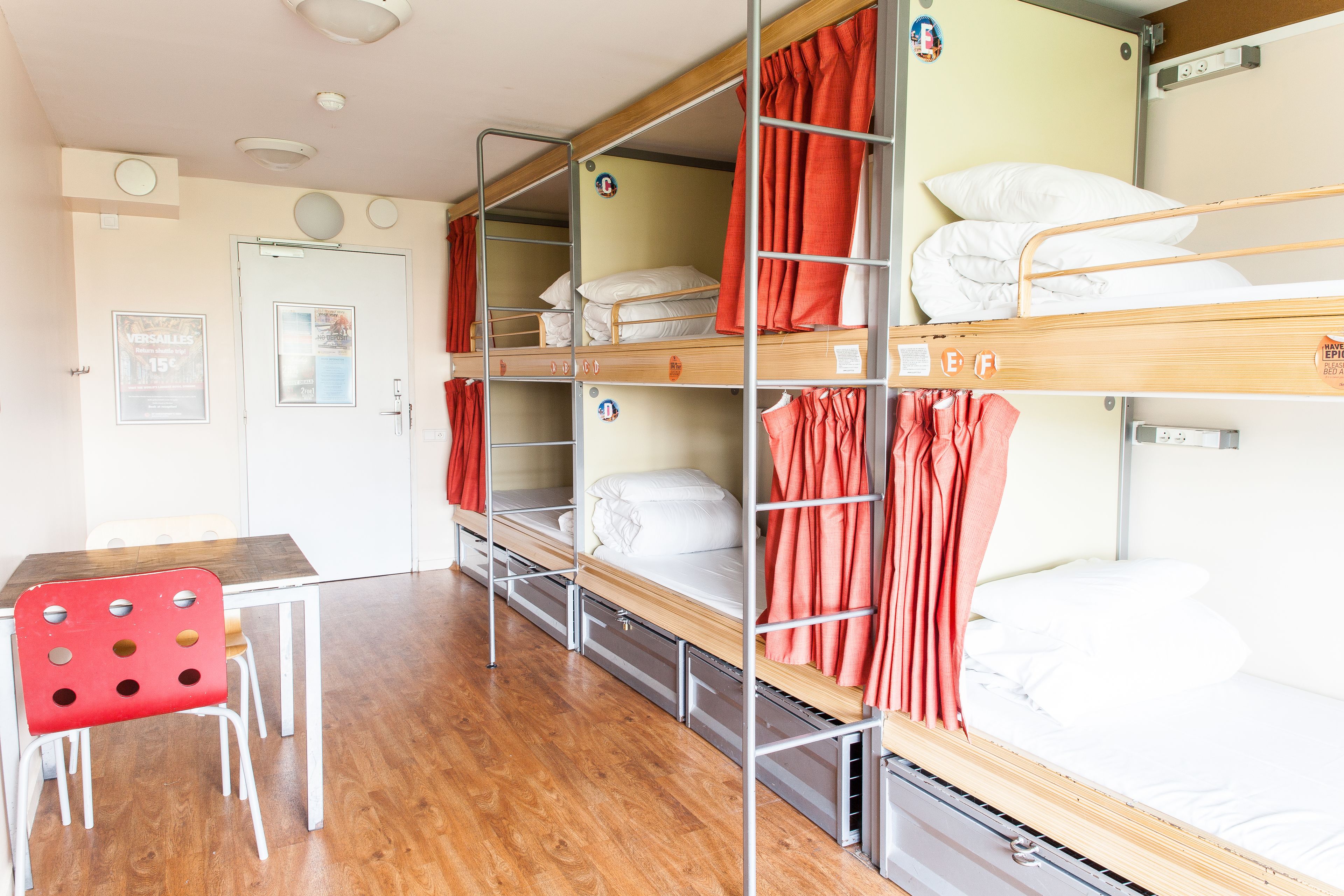 A dormitory room with bunk beds, a desk, and a chair.
