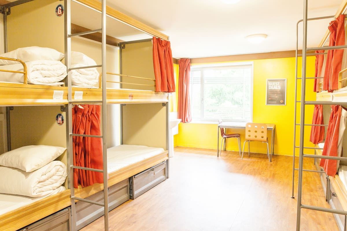 Un dormitorio con literas, un escritorio, una silla y una ventana con cortinas.