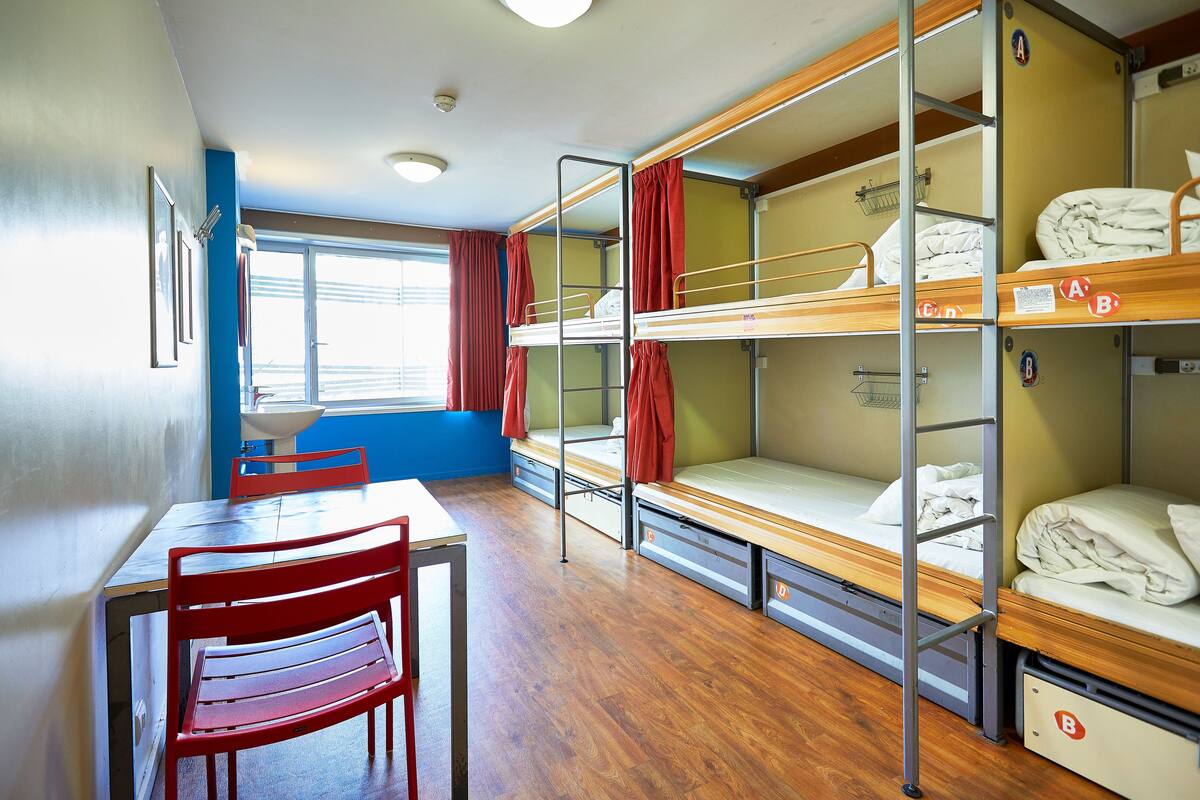 Un dormitorio con literas, una mesa y sillas.