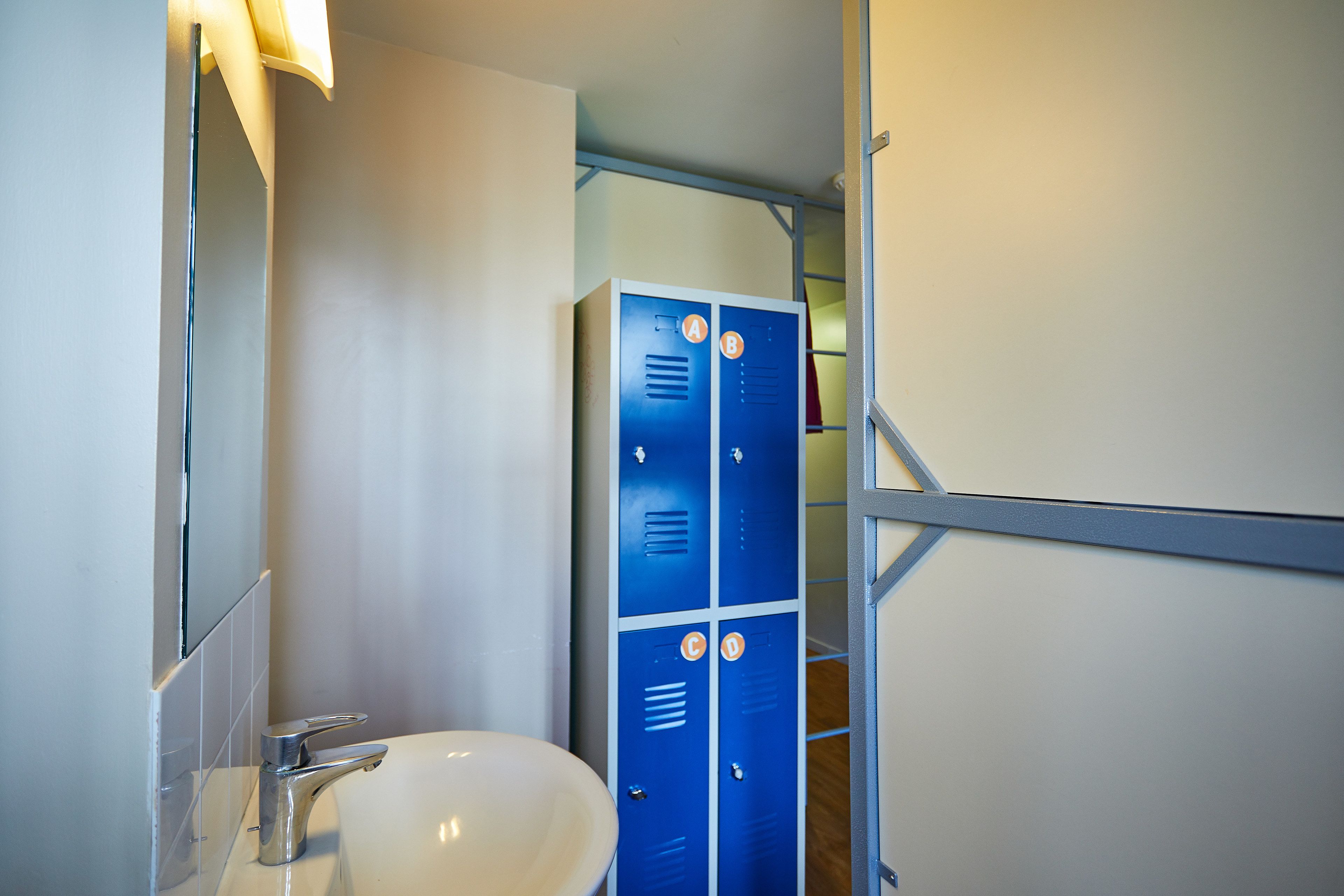 A bathroom with a white sink, a mirror, and blue lockers.