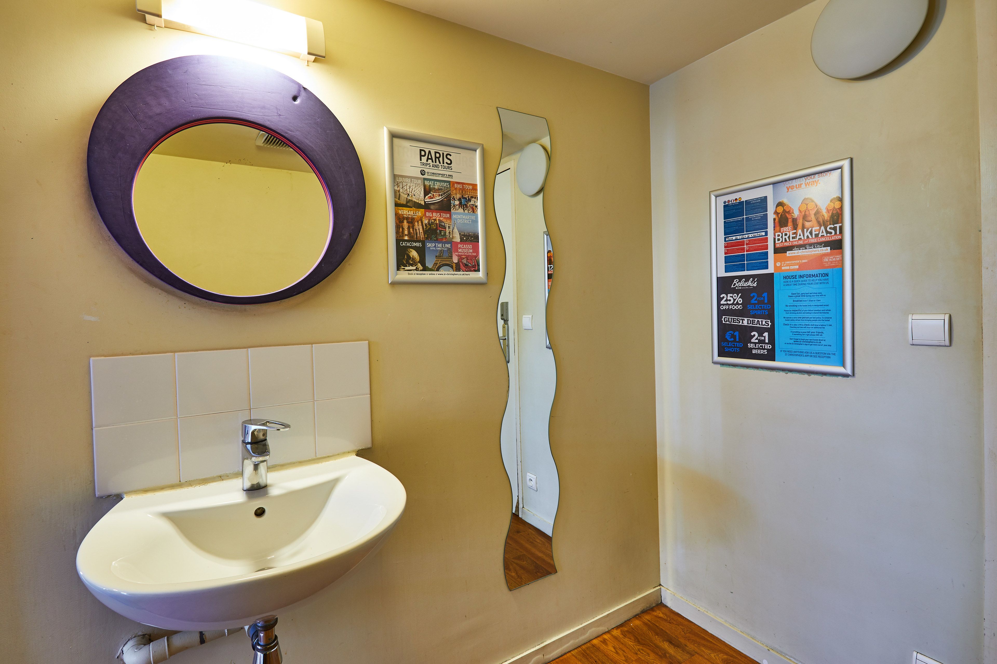 Une salle de bain avec un lavabo, un miroir et une affiche accrochée au mur.