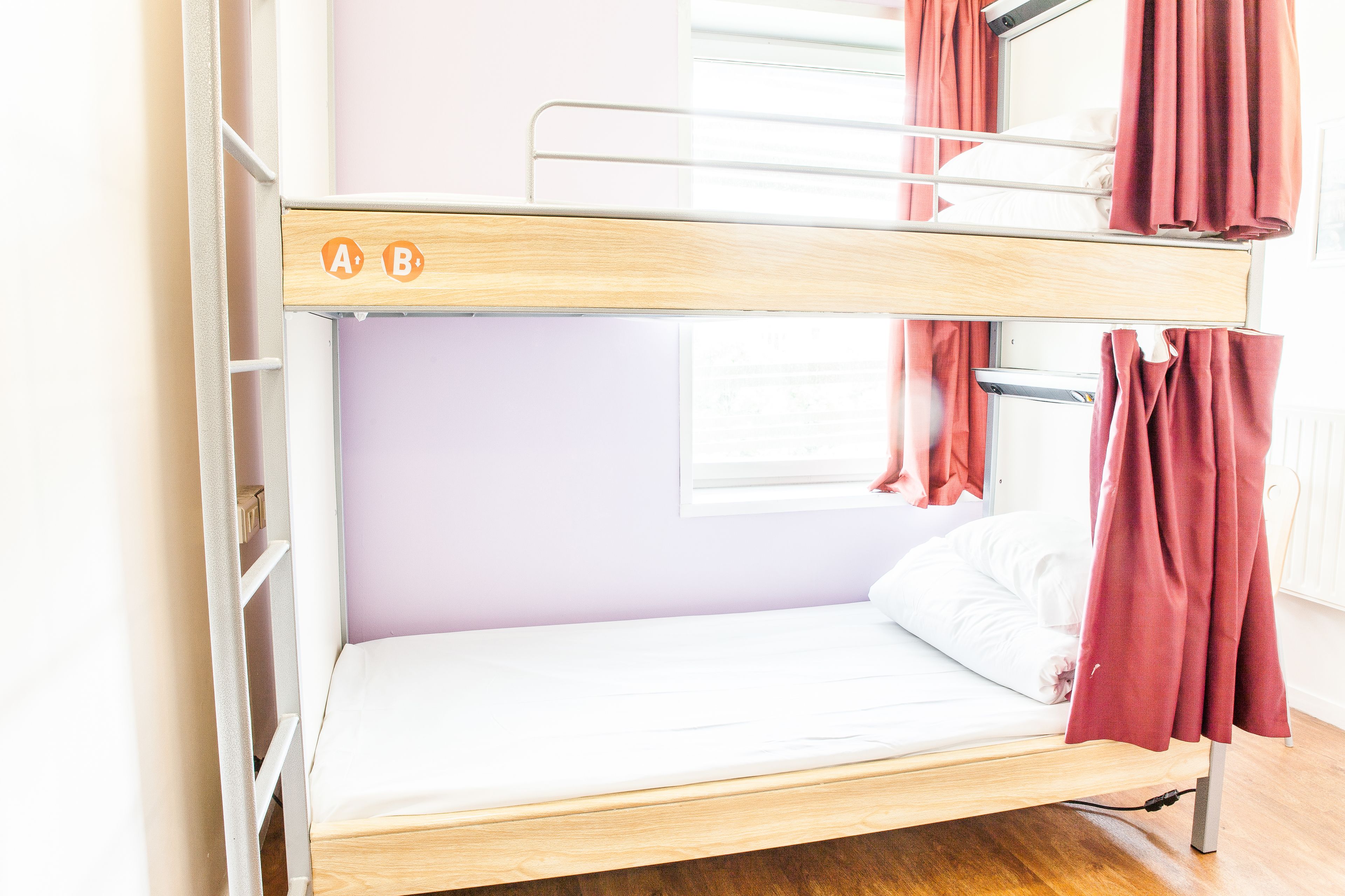 A bunk bed with a wooden frame and a lower bed with white bedding.