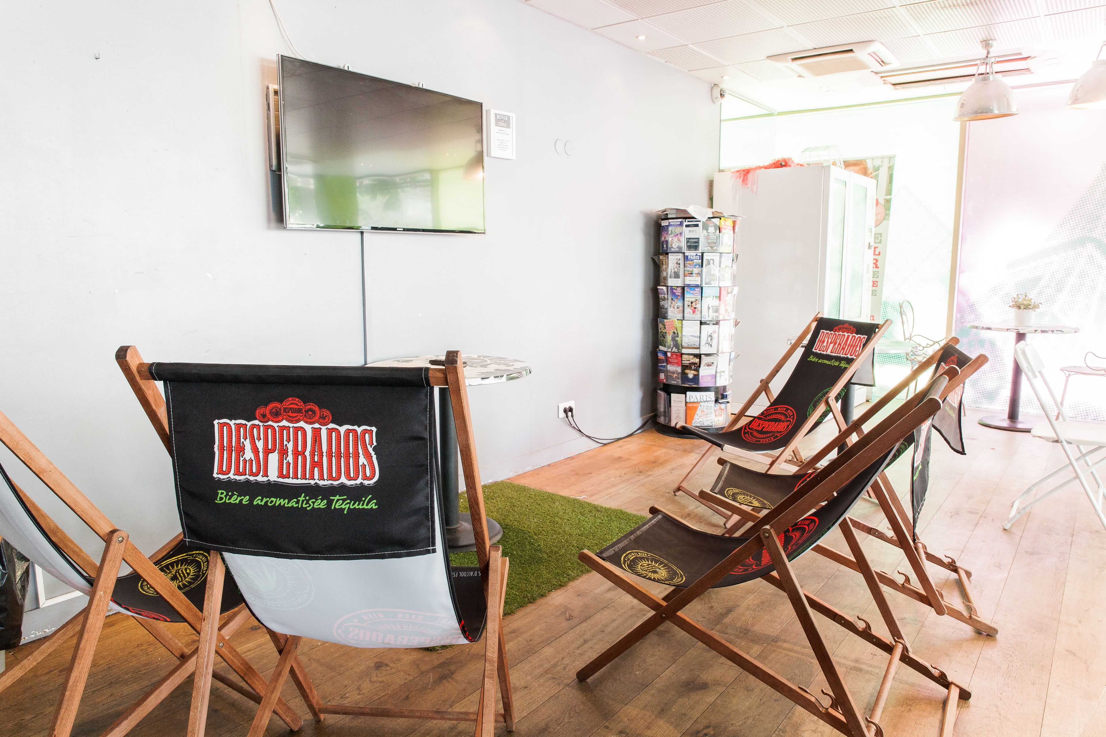 A room with two folding chairs, a television mounted on the wall, and a magazine rack.