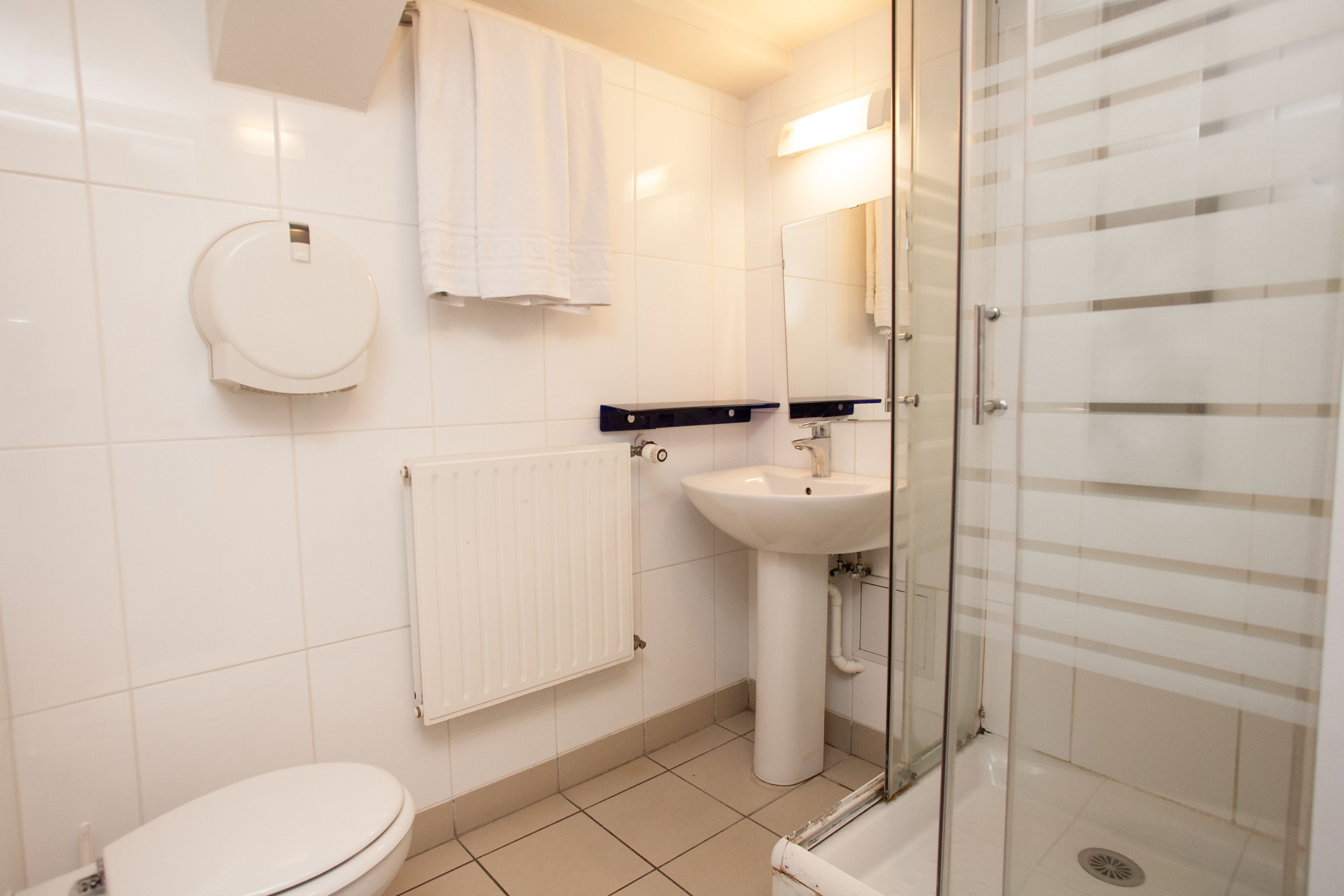 Een moderne badkamer met toilet, wastafel en douchecabine met glazen wanden.
